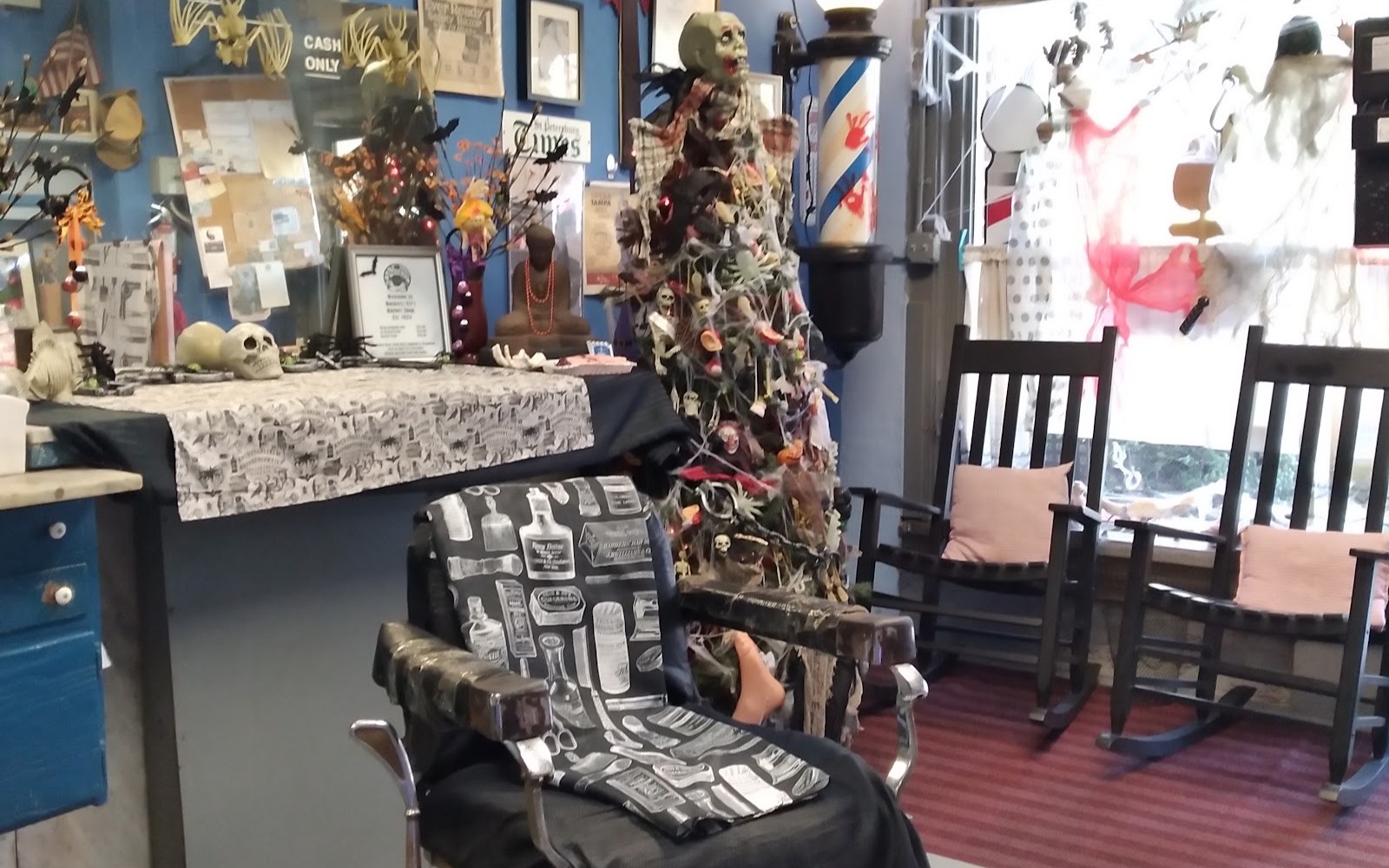 Inside the shop: a vintage barber chair, rocking chairs by the front window, and walls covered in old signs, framed photos and seasonal decorations.